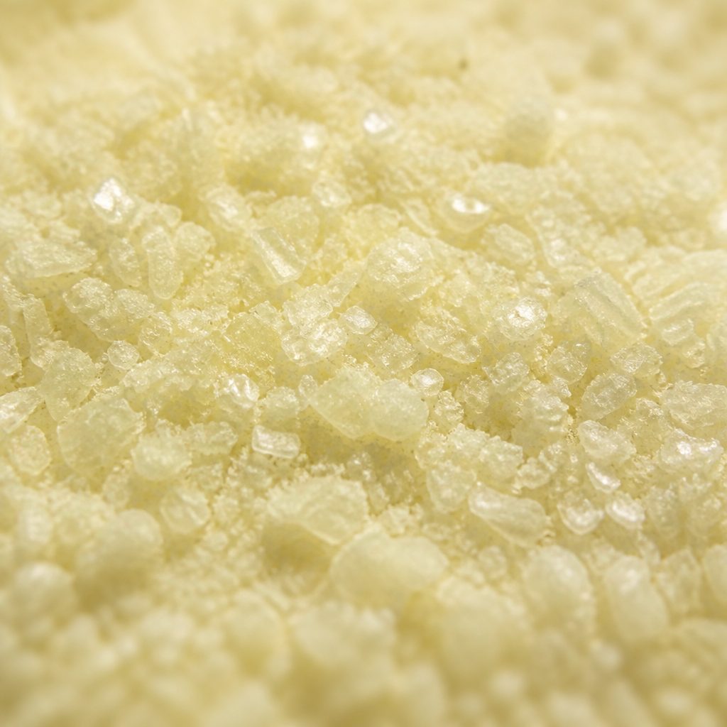 Pale yellow crystalline ubiquinol powder texture close-up